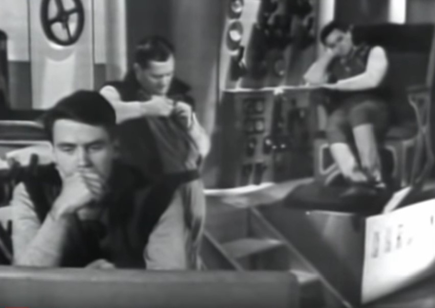 A screen cap from the TV show Space Command, showing James Doohan and two other actors on the bridge. Doohan's character is shown to be asleep at his station.